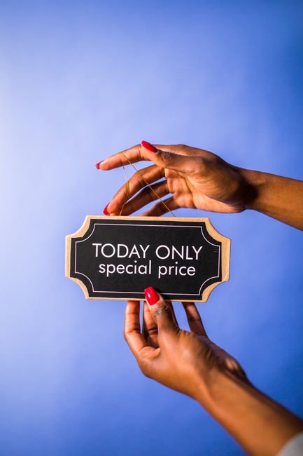 A pair of hands holding a small, black rectangular sign with a gold border, displaying the text 'TODAY ONLY special price' in white letters. The hand on the left, which has red-painted nails, supports